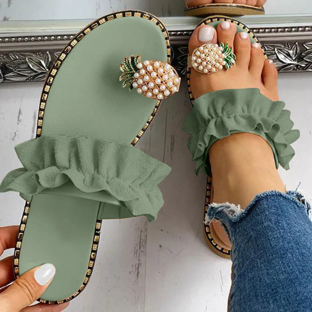 Green sandals with ruffles and pearl embellishments worn by a person.