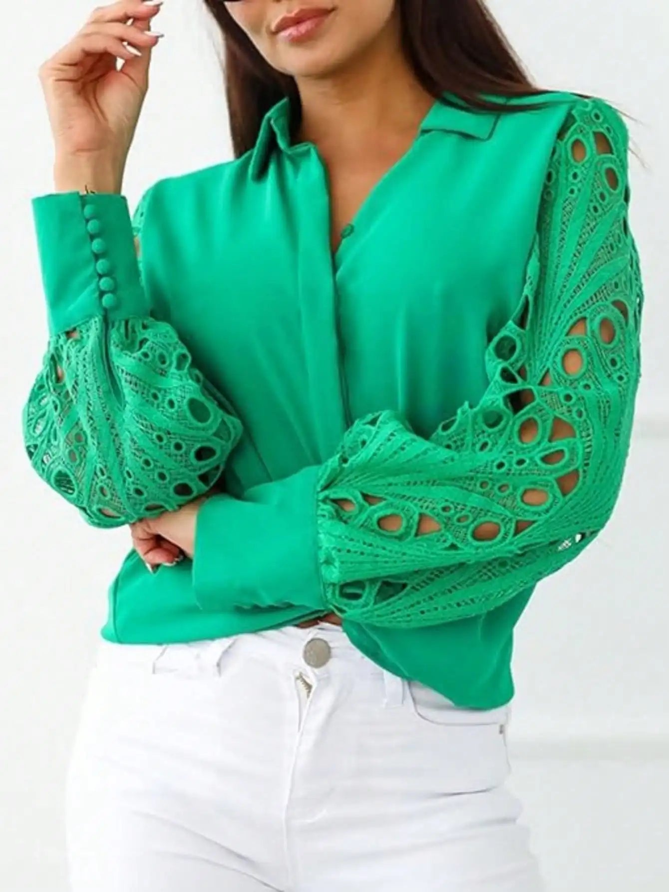 Green blouse with lace sleeves worn by a person on a white background