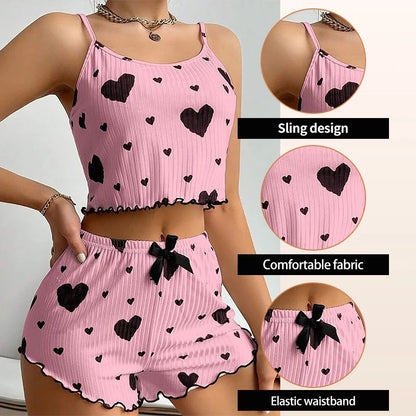 Pink pajama set with black heart patterns on a person, showing close-ups of sling design, comfortable fabric, and elastic waistband. Soft women’s pajama set, 2 pieces white tank top and shorts, breathable fabric with love print, comfortable casual sleepwear, UK FTF Market.