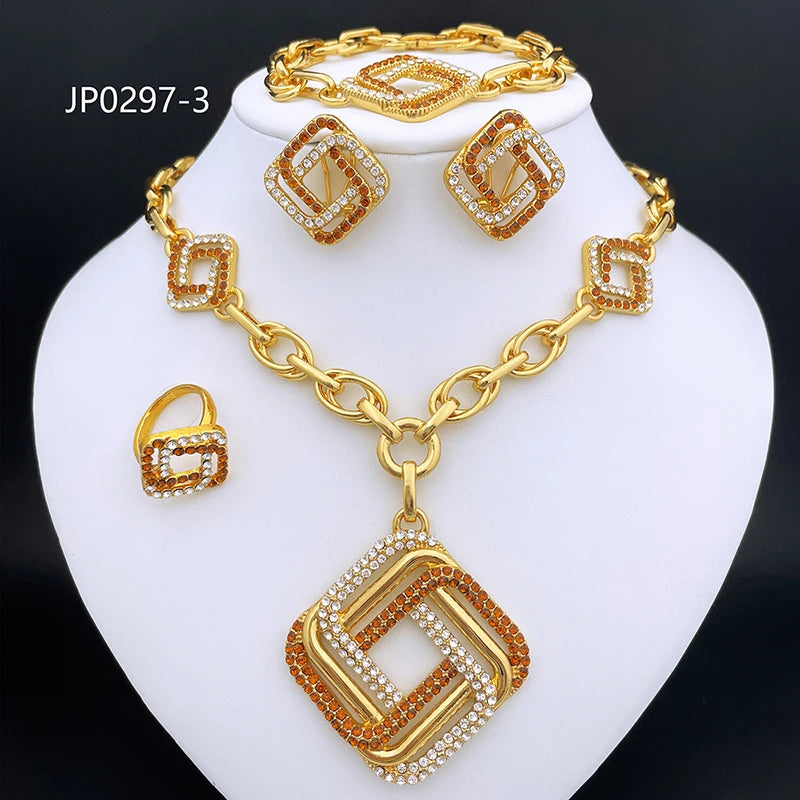 Gold-tone jewelry set on a white display bust, including a necklace with a large geometric pendant, matching earrings, and a ring, all decorated with clear rhinestones and orange-brown accents. The set is photographed against a black background.