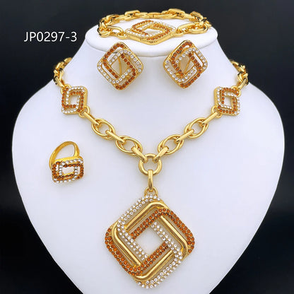Gold-tone jewelry set on a white display bust, including a necklace with a large geometric pendant, matching earrings, and a ring, all decorated with clear rhinestones and orange-brown accents. The set is photographed against a black background.
