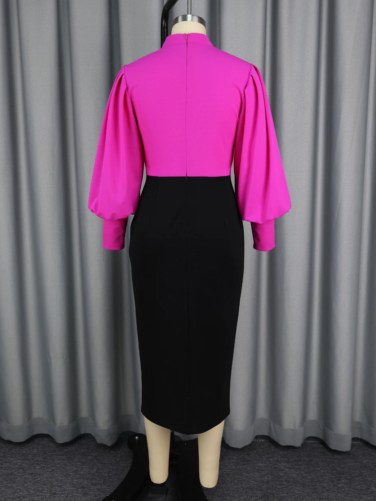 Mannequin wearing a bright pink top and black skirt against a gray curtain background