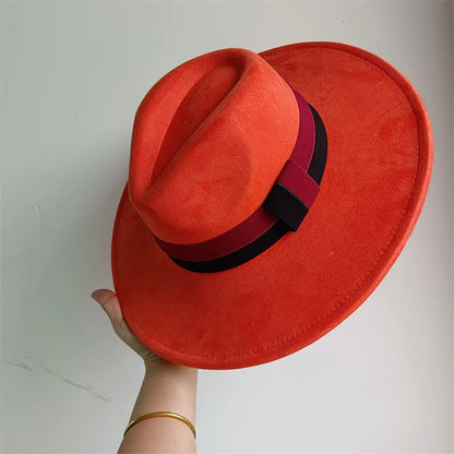 Red fedora hat with a black band held by a hand against a plain background