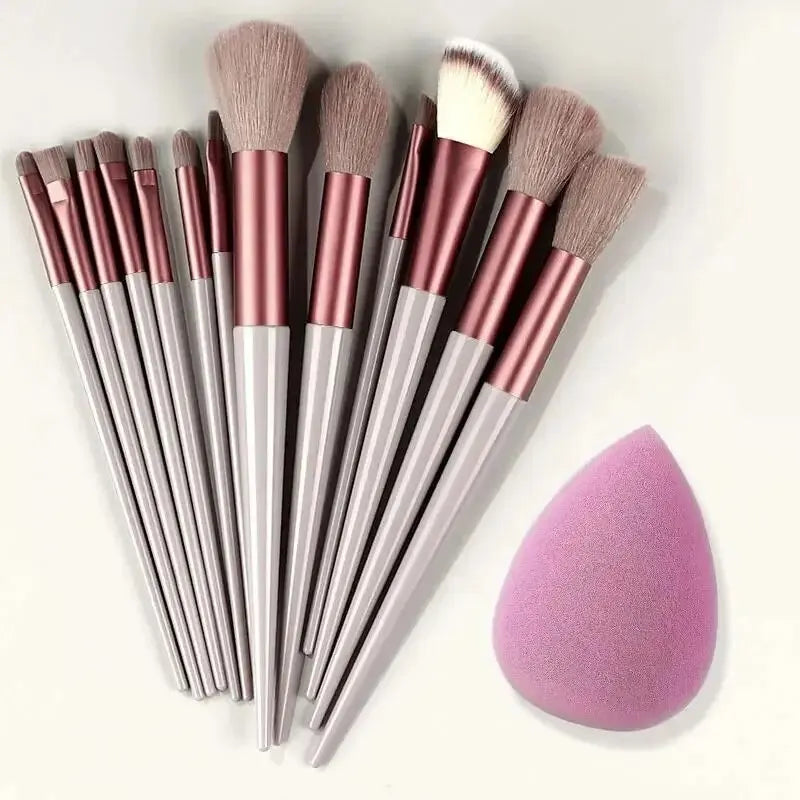 Set of makeup brushes with pink bristles and a pink makeup sponge on a white background. Soft fluffy makeup brush set with wool fiber bristles and plastic handles. Complete set for powder, foundation, eyeshadow, and beauty blending.