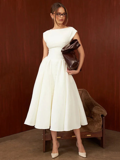 Woman in a white dress holding a brown leather clutch against a brown background