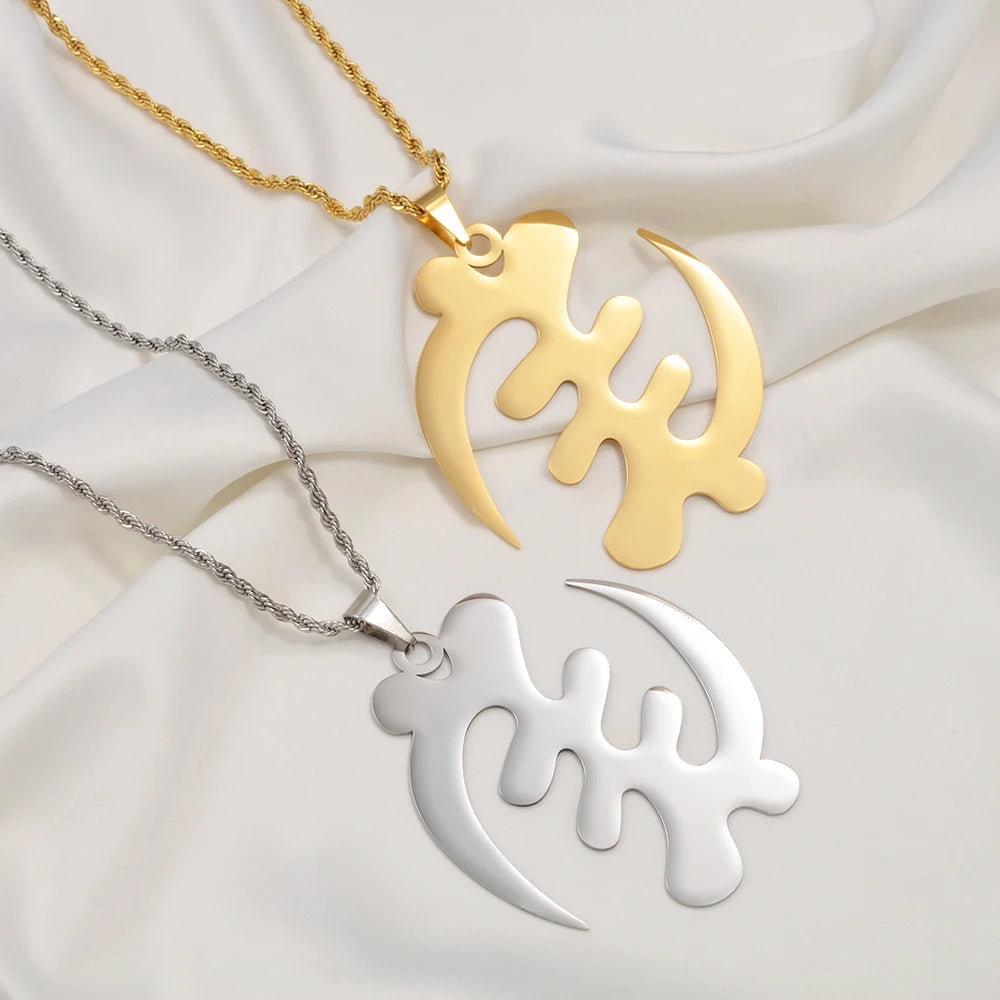 Two gold and silver necklaces with unique pendants on a white fabric background