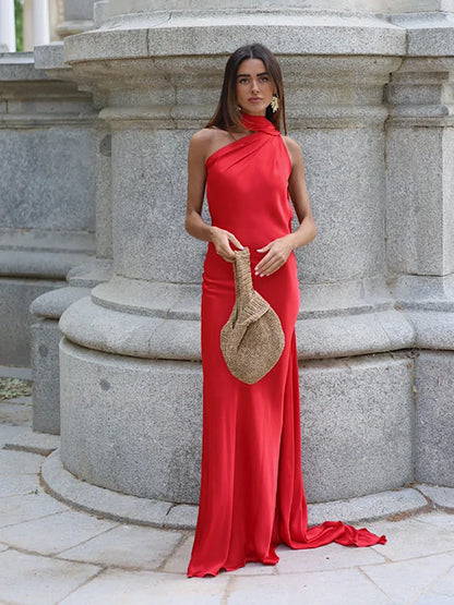 Woman in a red dress holding a straw bag against a stone architectural background