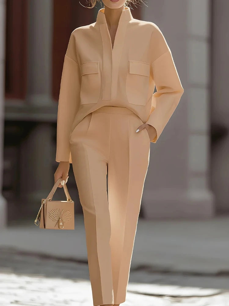 Person wearing a beige outfit with a matching handbag in an outdoor setting