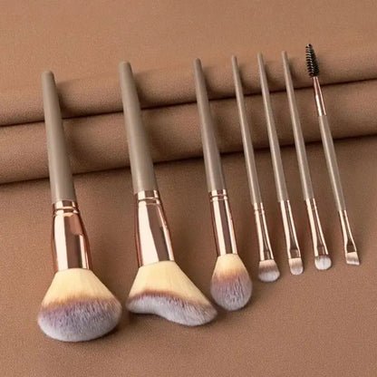 Set of makeup brushes with rose gold handles on a brown background. Soft fluffy makeup brush set with wool fiber bristles and plastic handles. Complete set for powder, foundation, eyeshadow, and beauty blending.