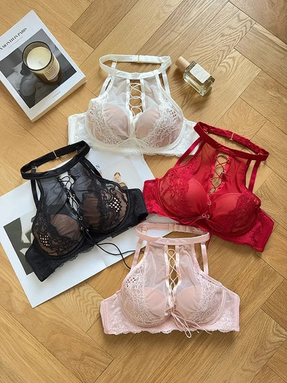 Four bras in black, white, red, and pink on a wooden floor with a magazine and bottle.