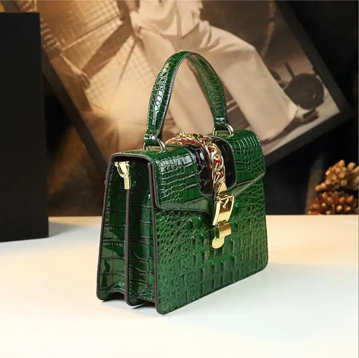 Green crocodile-patterned handbag with gold accents on a light surface. Small genuine leather crocodile crossbody bag. Hard flap design with soft handle, zipper closure, and interior phone & compartment pockets.