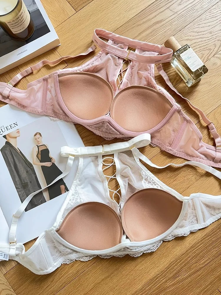 Two bras, one pink and one white, on a wooden surface with a magazine and perfume bottle in the background.