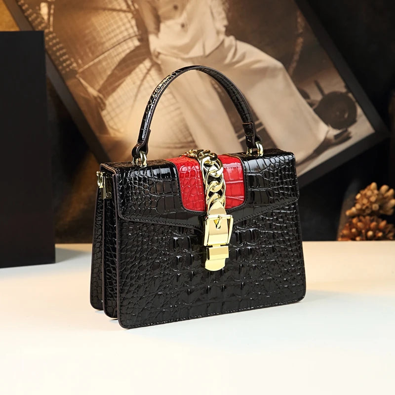 Black crocodile-patterned handbag with red accents and gold chain detail on a light surface Small genuine leather crocodile crossbody bag. Hard flap design with soft handle, zipper closure, and interior phone & compartment pockets.