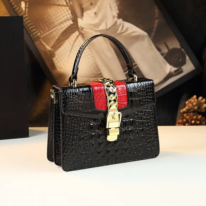 Black crocodile-patterned handbag with red accents and gold chain detail on a light surface Small genuine leather crocodile crossbody bag. Hard flap design with soft handle, zipper closure, and interior phone & compartment pockets.