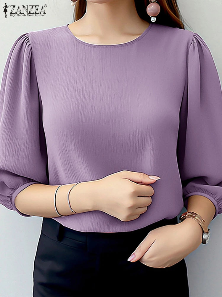 Purple blouse with puffed sleeves worn by a person on a plain background