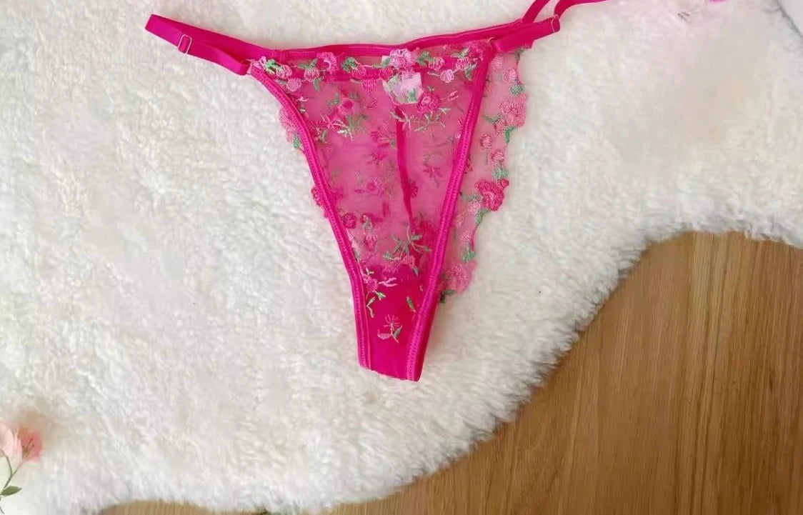 Pink lace lingerie with floral patterns on a white surface