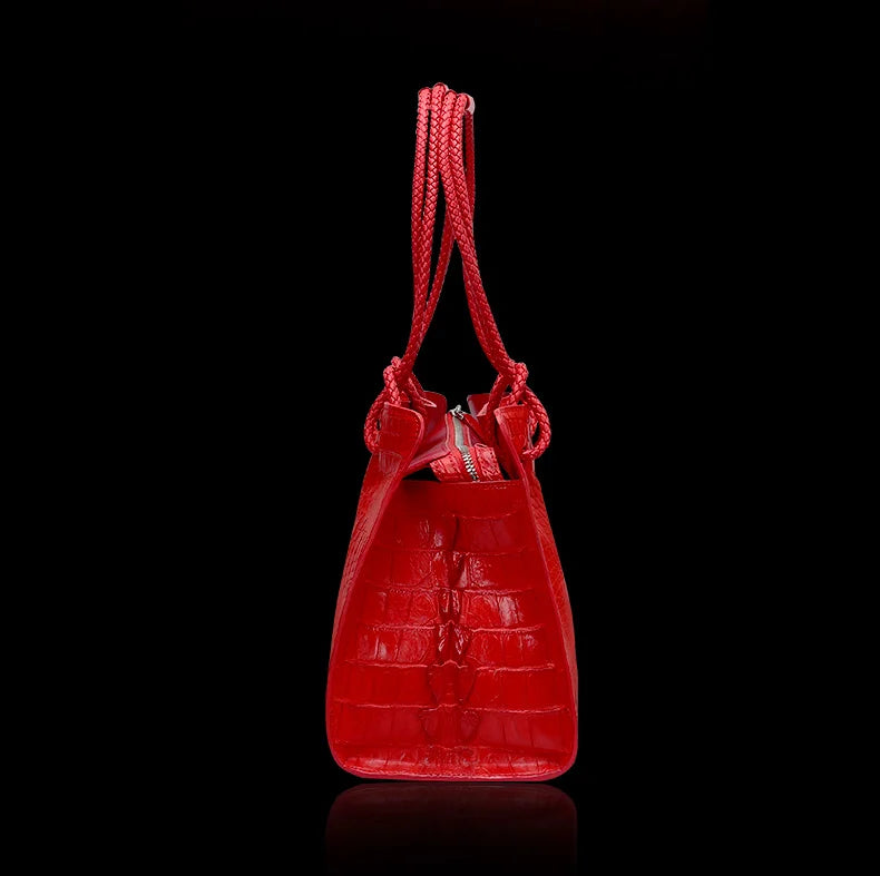 Red handbag with a textured pattern on a black background. Luxury women’s tote bag in genuine red crocodile leather. Large capacity, stylish handle, fashion travel handbag. Perfect for shoulder or portable use UK.