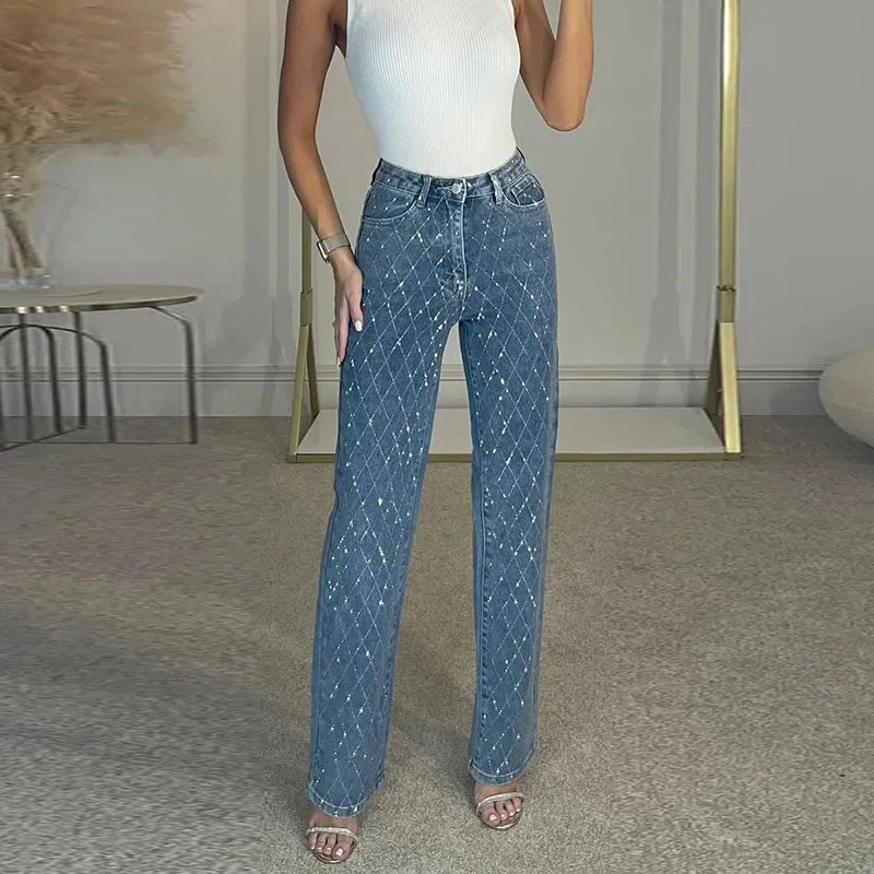 Person wearing blue jeans and a white top in an indoor setting. Women’s denim jeans with flower rhinestones, loose wide leg, low waist, light wash. Stylish rhinestone casual trousers for UK fashion lovers.