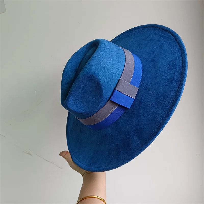 Blue fedora hat with a gray band held by a hand against a light gray background