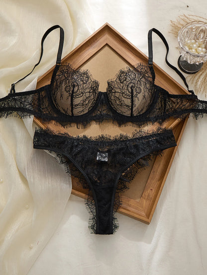 Black lace lingerie set on a wooden tray with a white fabric background