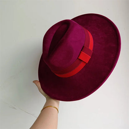 Purple hat with a red band held by a hand on a white background