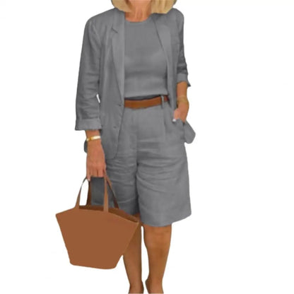 Image of a woman wearing a white Linen Look Blazer and Bermuda Shorts Co-ord Set with a brown belt and straw bag. Ideal smart casual summer outfit.