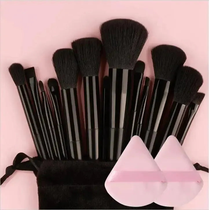 Set of makeup brushes with a black pouch and pink containers on a pink background. Soft fluffy makeup brush set with wool fiber bristles and plastic handles. Complete set for powder, foundation, eyeshadow, and beauty blending.