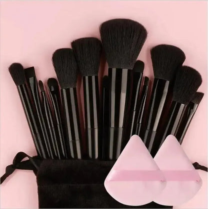 Set of makeup brushes with a black pouch and pink containers on a pink background. Soft fluffy makeup brush set with wool fiber bristles and plastic handles. Complete set for powder, foundation, eyeshadow, and beauty blending.