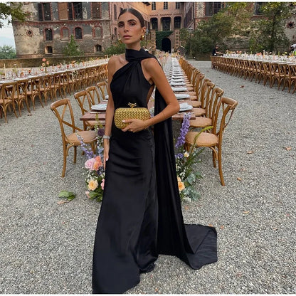 Woman in a black dress standing in front of an outdoor event setup with tables and chairs.