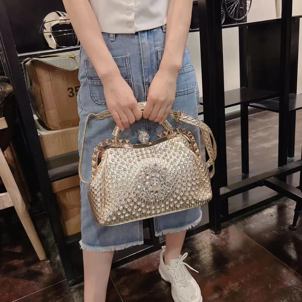 Person holding a decorative handbag in an indoor setting. Large genuine leather dumpling bag with diamond rhinestone clip and lock clasp. Soft handle, multiple compartments. Fashionable shoulder tote for women.