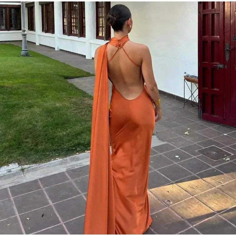 Woman in an orange dress with a high slit standing on a tiled patio.