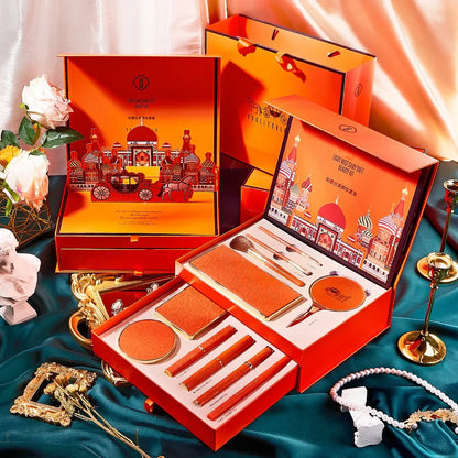 Orange cosmetic set with decorative packaging on a blue fabric background. Christmas makeup gift box with BB cream, lipstick, eyeshadow, eyebrow pencil, and brushes. Holiday beauty set for women & girls.