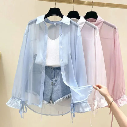 Two sheer shirts, one light blue and one pink, on hangers against a beige background.