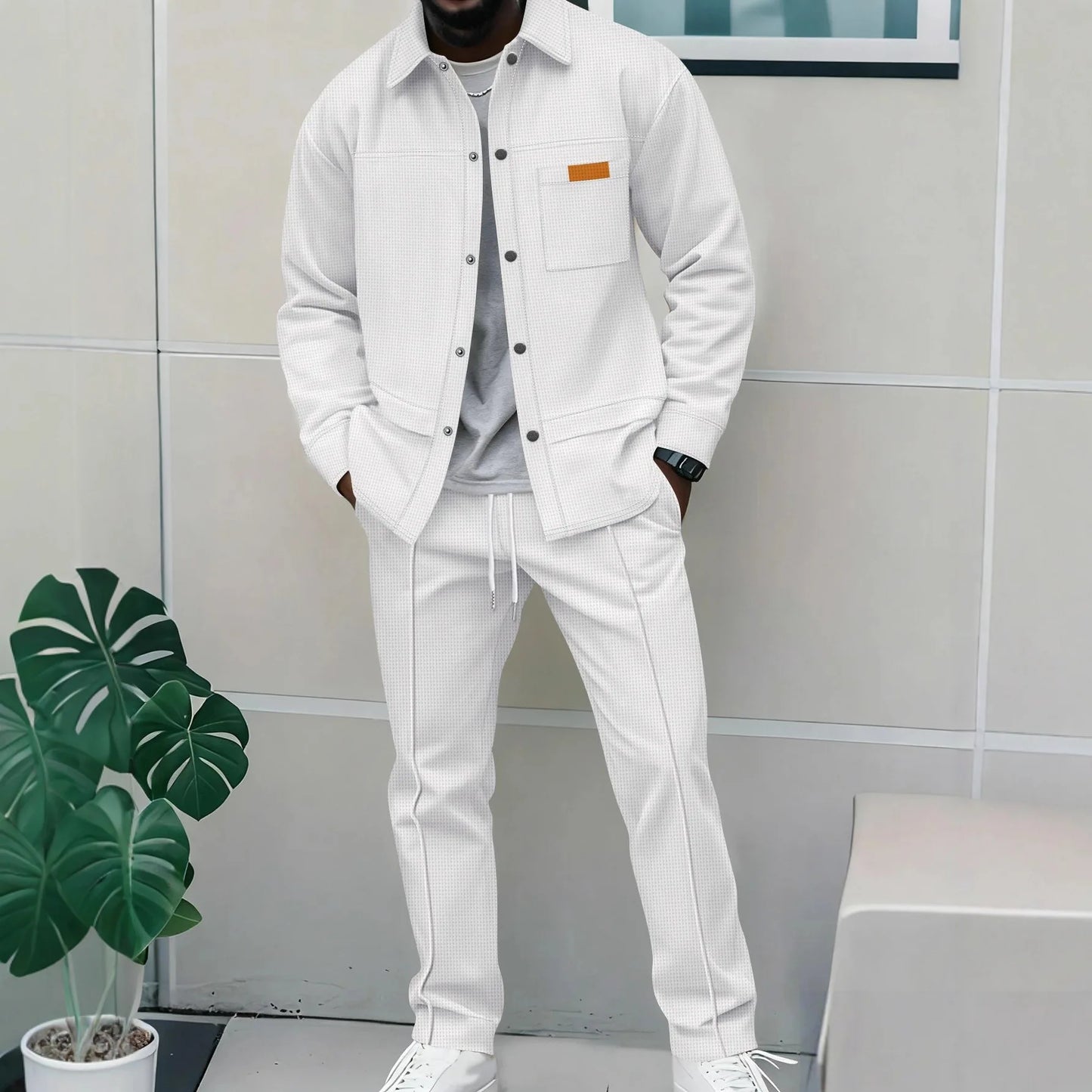 Person wearing a white outfit with a gray wall and plant in the background