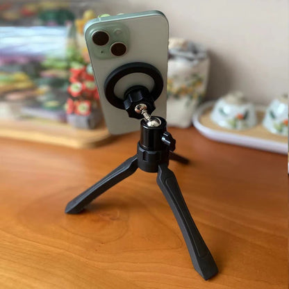 Phone with a tripod stand on a wooden surface. Magnetic phone tripod and wireless grip with remote control. Fits iPhone MagSafe and Samsung devices. Lightweight selfie stick tripod for creators.