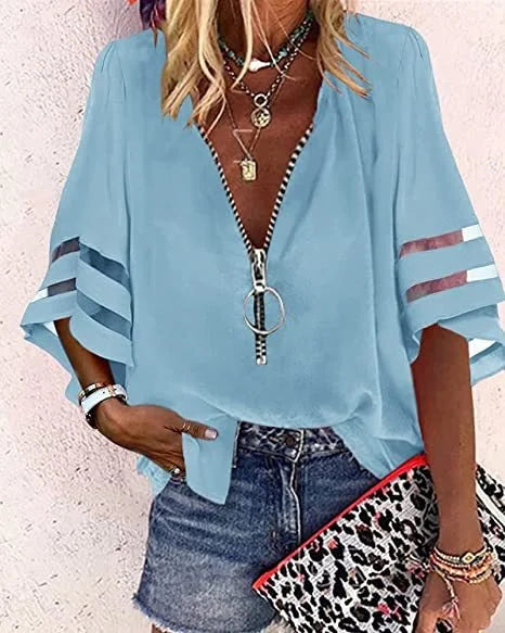 Light blue blouse with a zipper detail worn by a person, with a leopard print clutch in the foreground.