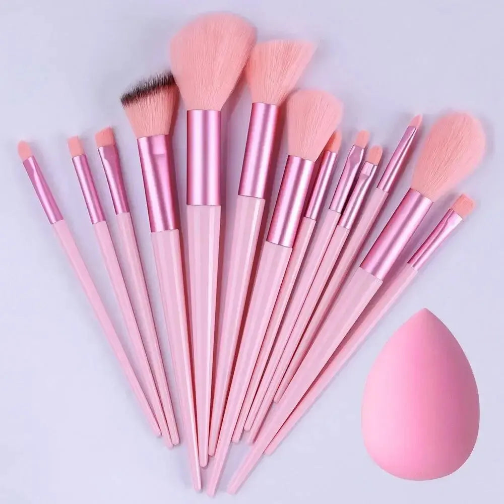 Set of pink makeup brushes with a pink sponge on a light gray background. Soft fluffy makeup brush set with wool fiber bristles and plastic handles. Complete set for powder, foundation, eyeshadow, and beauty blending.