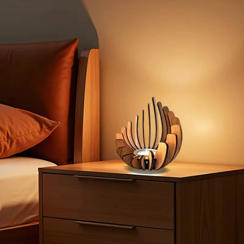 Wooden lamp on a nightstand next to a bed with orange pillows.