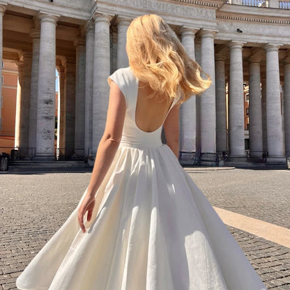 Woman in a white dress standing in front of a classical building with columns.