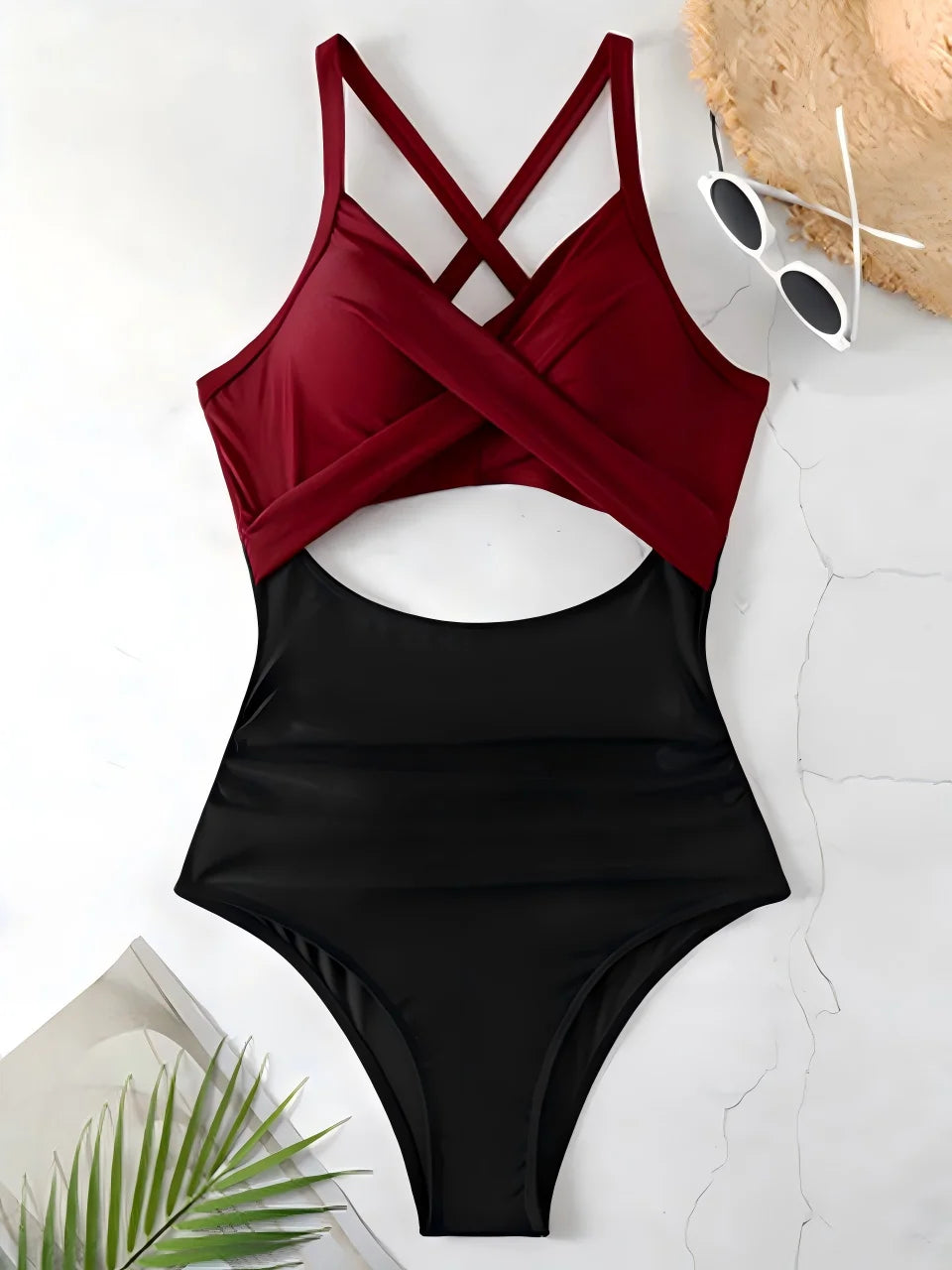 Black and red swimsuit with sunglasses and a hat on a light background