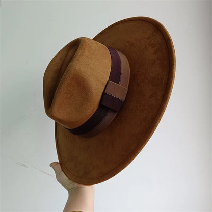 Brown suede hat with a wide brim and ribbon on a light gray background