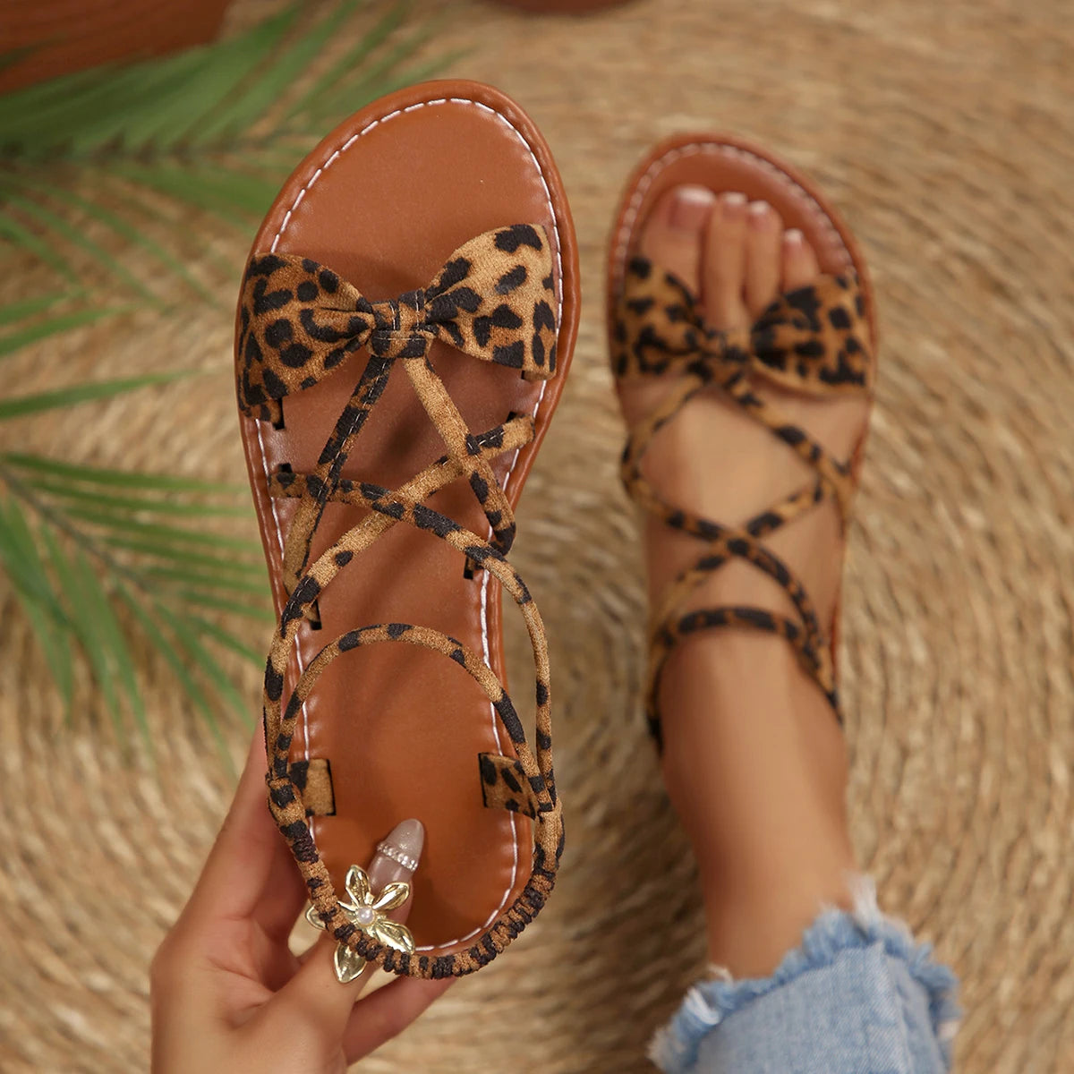 Leopard print sandals held by a person on a woven surface