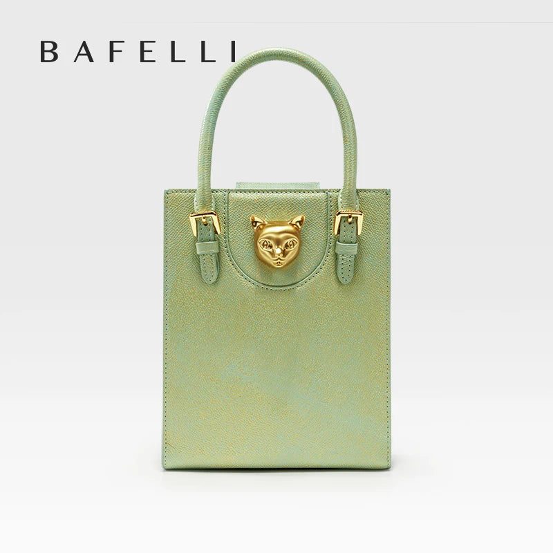 Green handbag with gold accents on a light gray background, featuring the brand 'Bafelli'. Unisex mini tote crossbody bag in split leather with flap pocket and lock closure. Hard box shape and polyester lining. Casual versatile style.