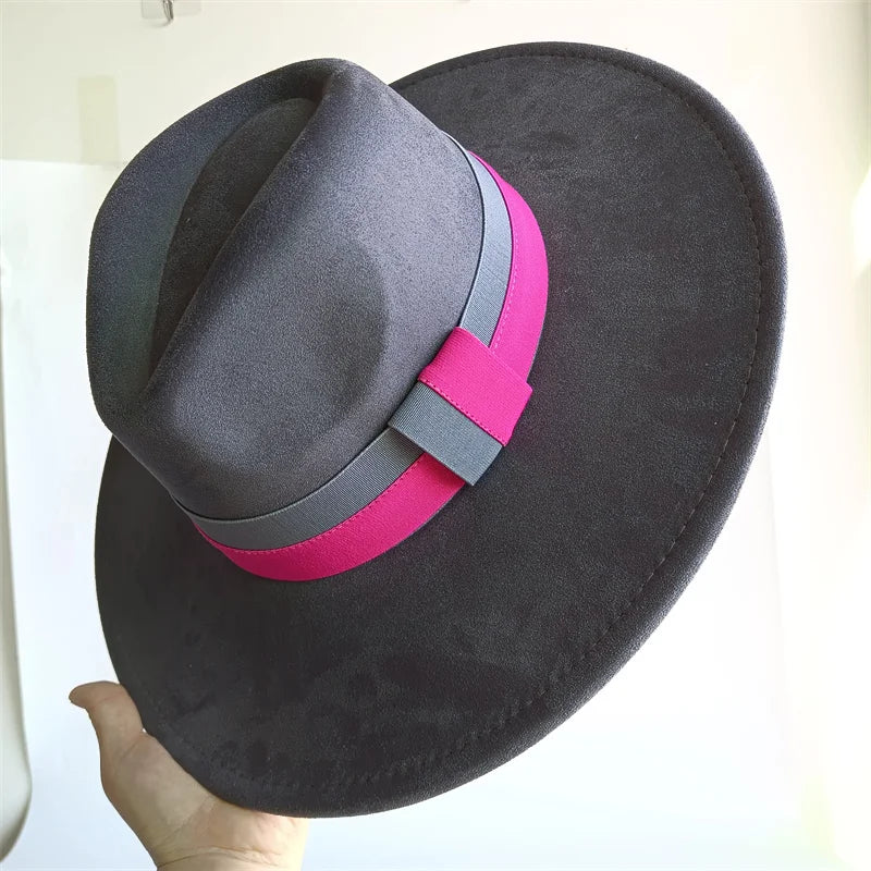Black hat with a pink and gray band held by a hand against a white background