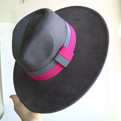 Black hat with a pink and gray band held by a hand against a white background