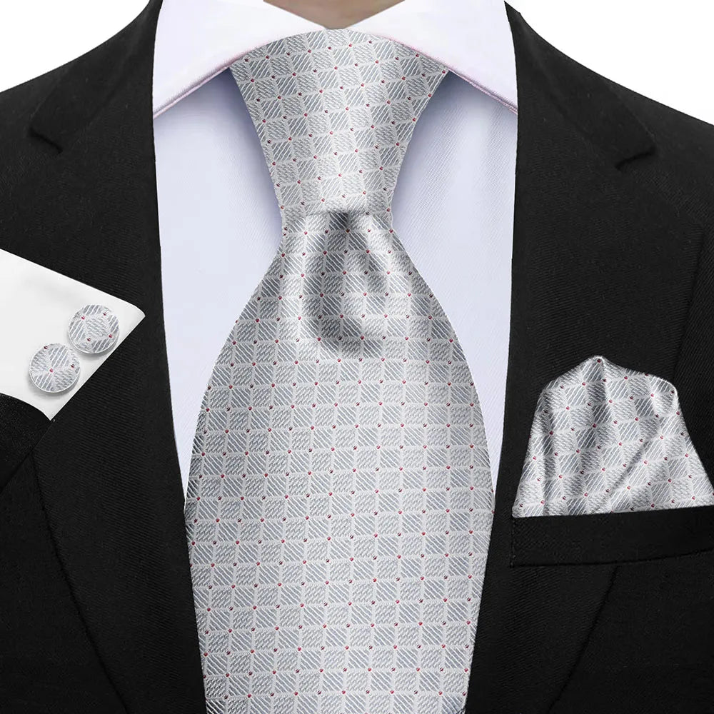 Gray patterned tie with matching pocket square and cufflinks on a black suit. Elegant men’s 3-piece tie set: striped necktie, floral pocket square, matching cufflinks. Fashionable polyester accessories for formal occasions.