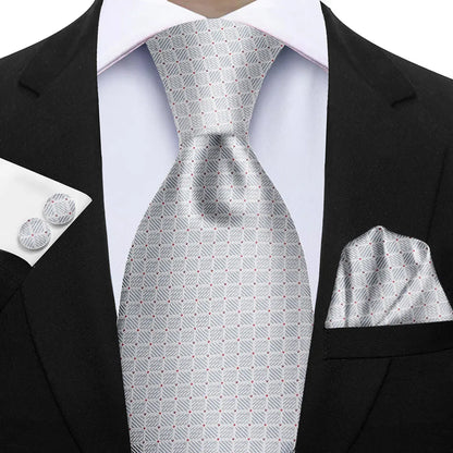 Gray patterned tie with matching pocket square and cufflinks on a black suit. Elegant men’s 3-piece tie set: striped necktie, floral pocket square, matching cufflinks. Fashionable polyester accessories for formal occasions.