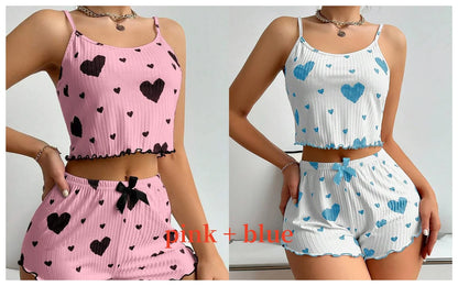 Two women wearing matching outfits with pink and blue heart patterns. Soft women’s pajama set, 2 pieces white tank top and shorts, breathable fabric with love print, comfortable casual sleepwear, UK FTF Market.