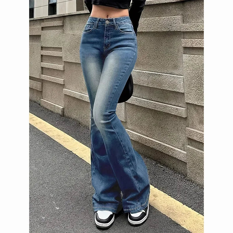 Person wearing blue flared jeans standing against a textured wall. Women’s high waist flared jeans, stretchy bootcut denim trousers. Thin fabric, solid color, bell bottoms style for casual chic UK fashion.