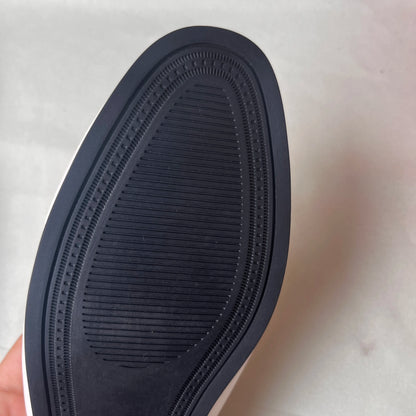 Close-up of a black shoe sole with tread pattern on a light background